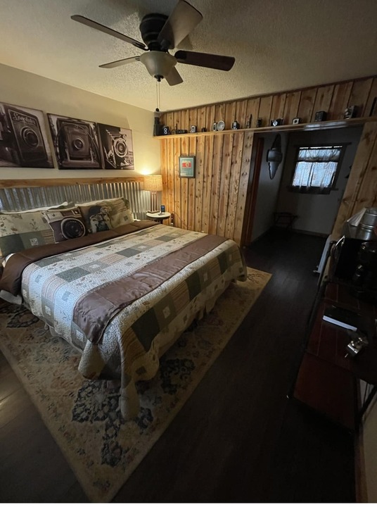 King-bed themed room with vintage camera prints above a corrugated metal headboard