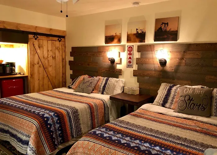 Twin-bed room with reclaimed-wood headboards, sunset oilfield art, and barn-door entry