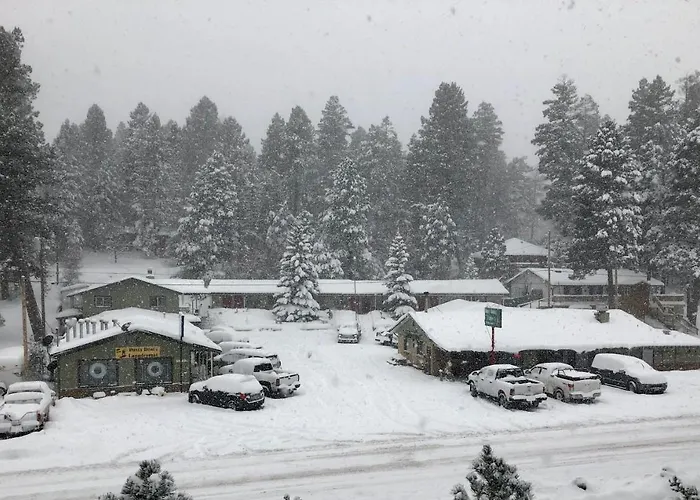 Dusty Boots Motel exterior in fresh snow, ringed by tall pines on James Canyon Highway