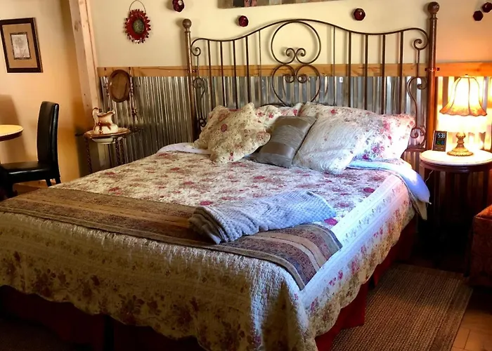 Cottage style king bed with iron scrollwork headboard and floral quilt under a tiffany lamp