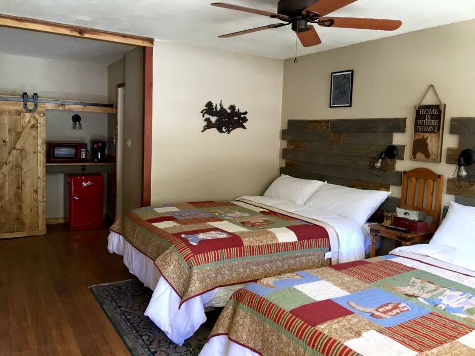 Western themed double-bed room with red retro fridge, barn-door closet, and patchwork quilts