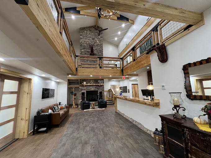 Two-story lobby with exposed white fir beams, stone fireplace, and front desk