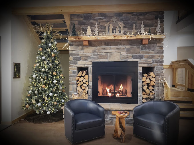 Stone fireplace with Christmas tree and leather club chairs in the lobby