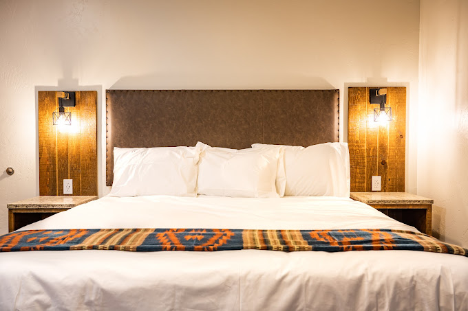 King bed with custom white fir headboard, sconce lighting, and Southwestern blanket