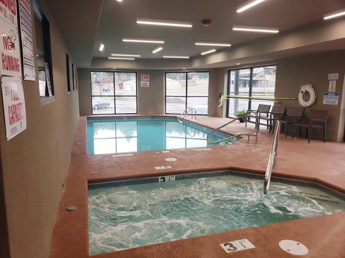 Indoor pool and hot tub with large windows overlooking the property