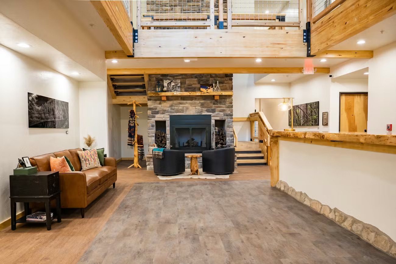 Lobby view showing stone fireplace, leather seating, and mezzanine level