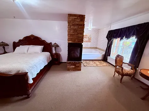 Suite bedroom with fireplace and soaking tub beyond