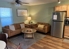 Sitting area at Osha Trail Lodging with two tan leather sofas, a round wood coffee table, and a framed mountain print