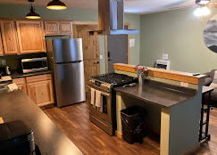 Wider kitchen view at Osha Trail Lodging with island bar separating from the dining area, hickory cabinets, and stainless steel appliances