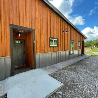 Modern wood-and-metal exterior at Osha Trail Lodging with a unit 4 entry door, gravel walkway, and concrete pad