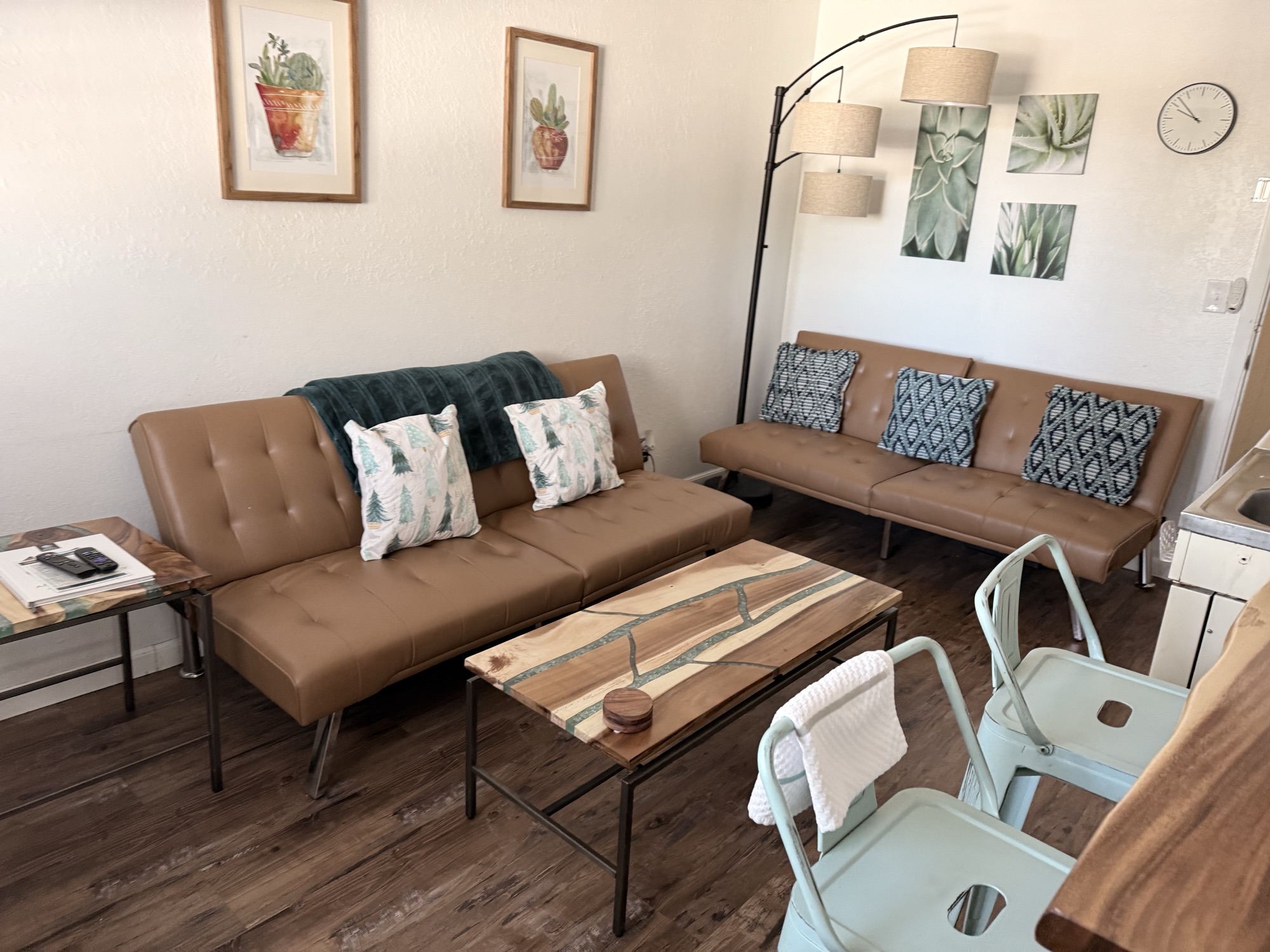 Suite living area at The Summit Inn with caramel leather sofa, agave wall art, mint industrial chairs, and a live-edge coffee table